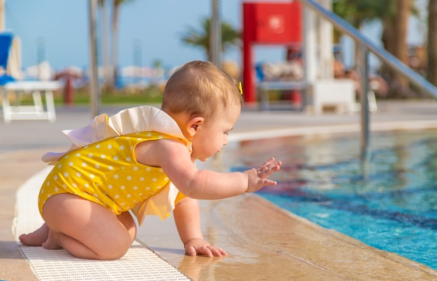 El bebé se mete en la piscina hasta el agua.