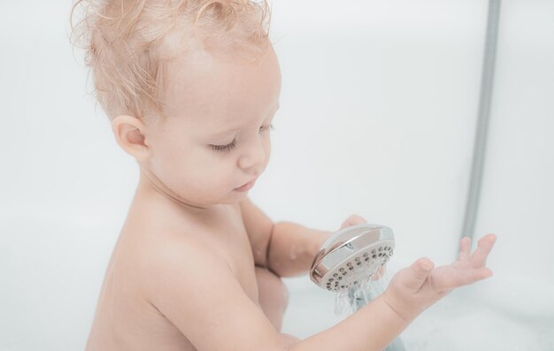 Bebê na banheira bebê feliz tomando banho brincando com a mãe e espuma bebê bebê tomando banho na banheira branca