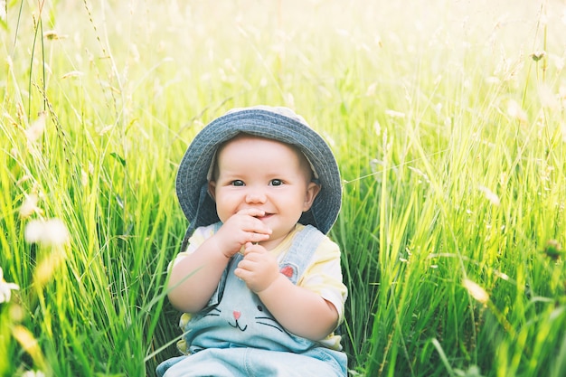 Bebé en la naturaleza La niña sonriente más linda en la hierba verde con flores en verano