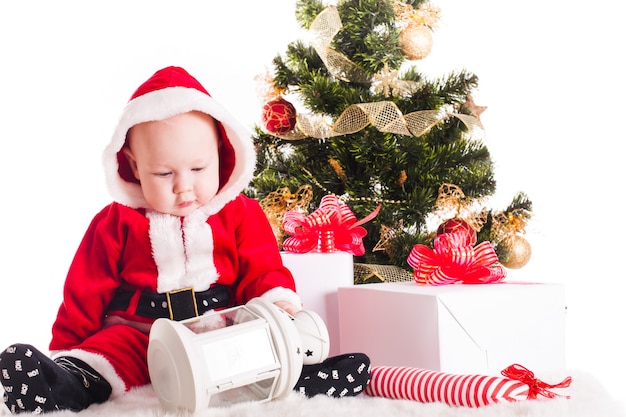 Bebé de Navidad bajo el árbol de año nuevo con regalos