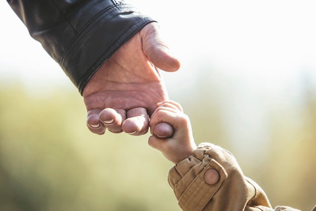 Bebé niña chaqueta cálida y gorra c abuelo manos en otoño Parque