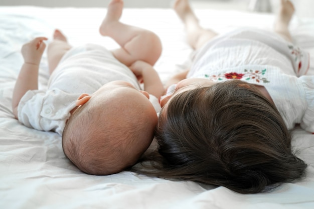 Bebé y niña están en la cama. Dos hermanitas yacen cerca.