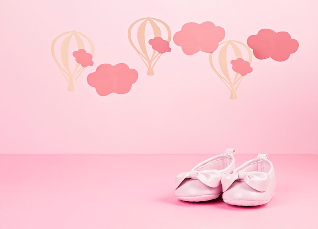 Bebé niña lindos zapatos rosas sobre el fondo rosa pastel con nubes y globos