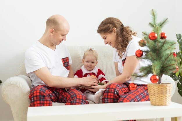 Bebé niño con audífono e implante coclear divirtiéndose con los padres en la sala de navidad Diversidad sorda y concepto de salud