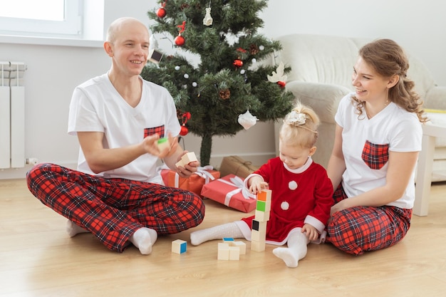 Bebé niño con audífono e implante coclear divirtiéndose con los padres en la sala de navidad Diversidad sorda y salud y diversidad