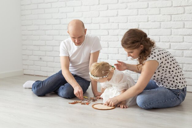 Bebé niño con audífonos e implantes cocleares juega con los padres en el piso Concepto de sordera y rehabilitación