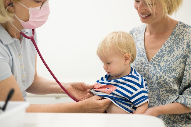 Bebé niño niño siendo examinado por su médico pediatra durante un chequeo médico estándar en