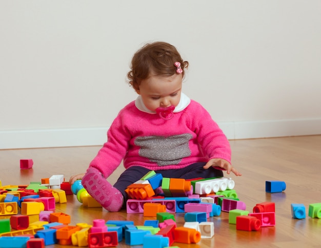 Bebé del niño que juega con los bloques huecos del caucho.