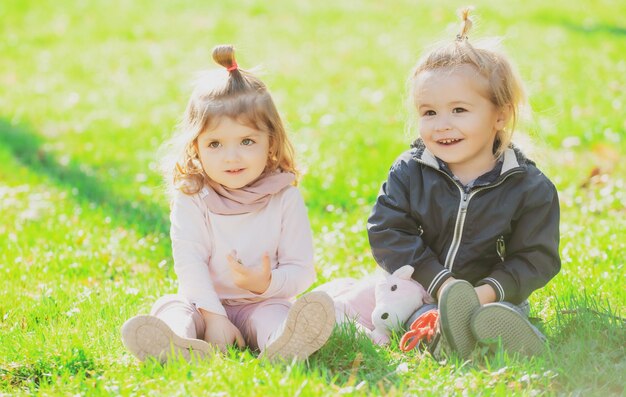 Bebé niño sobre la hierba verde en el parque de verano hermano y hermana juegan juntos en un prado verde feliz