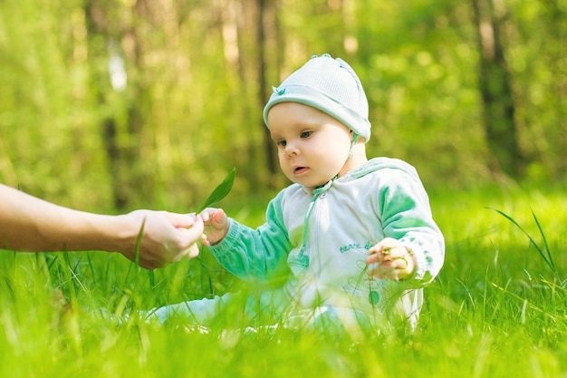 Bebê no parque pegando lençol verde nas mãos