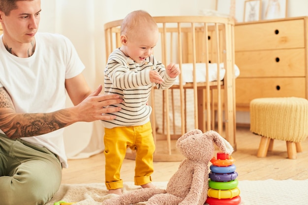 Foto bebé de nueve meses juega con papá en la habitación de los niños