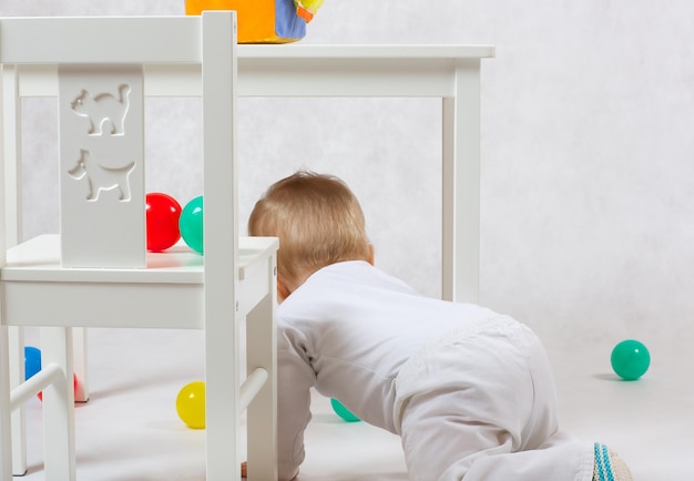 Un bebé de ocho meses está realizando algunas actividades sobre un fondo gris.