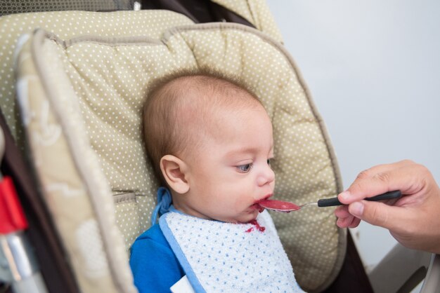 Bebé de ojos azules comiendo - en cochecito de bebé