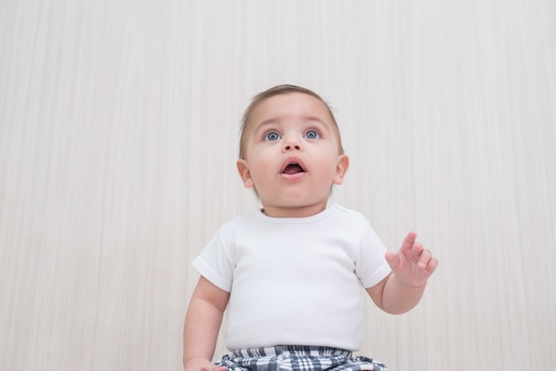 Bebé de ojos azules en el fondo de madera blanco