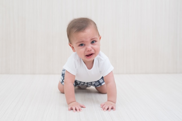 Bebé de ojos azules en el fondo de madera blanco