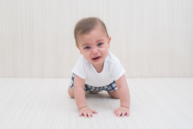 Bebé de ojos azules en el fondo de madera blanco