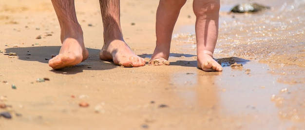 El bebé y el padre están caminando por la playa.