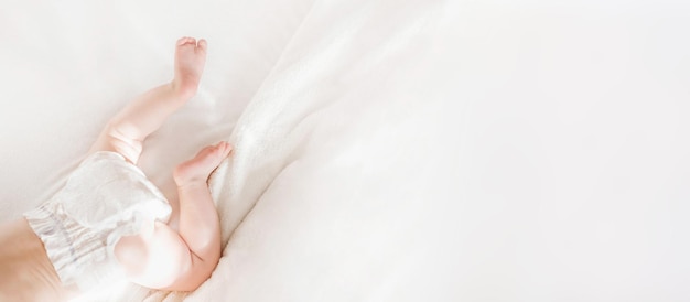 Bebé en un pañal yace en un espacio de copia de vista superior de cama blanca