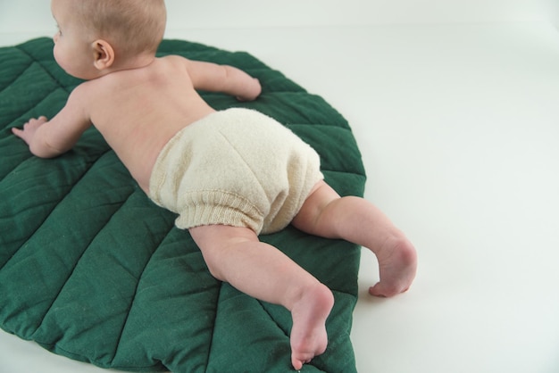bebé en pañales de lana reutilizables en una alfombra verde