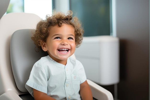 Bebé de pelo rizado en la silla del dentista sonriendo ampliamente mostrando sus dientes
