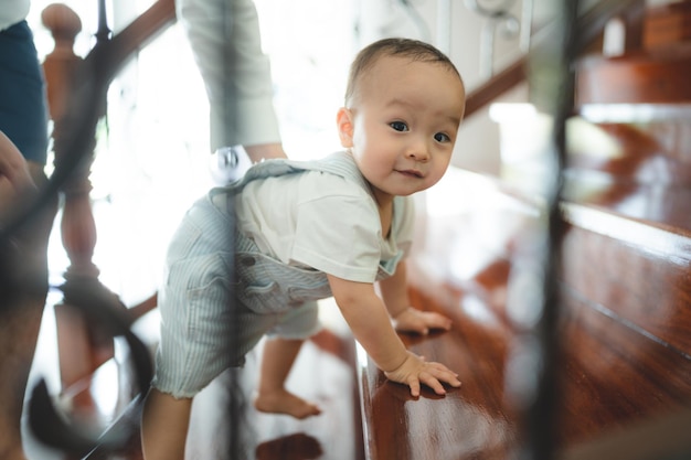 Bebé pequeño aprendiendo a caminar y con el apoyo de la familia juntos niño pequeño con padre y madre en casa con el primer paso para caminar con ayuda y tomados de la mano de papá cuidado de ayuda infantil feliz