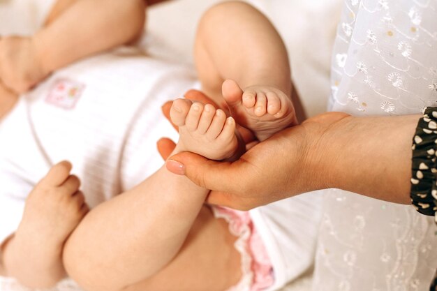 Bebê pezinhos de pele branca segurando na mão da mãe.