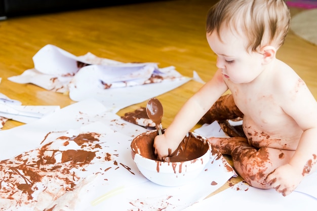 Bebé pintando con las manos con chocolate.