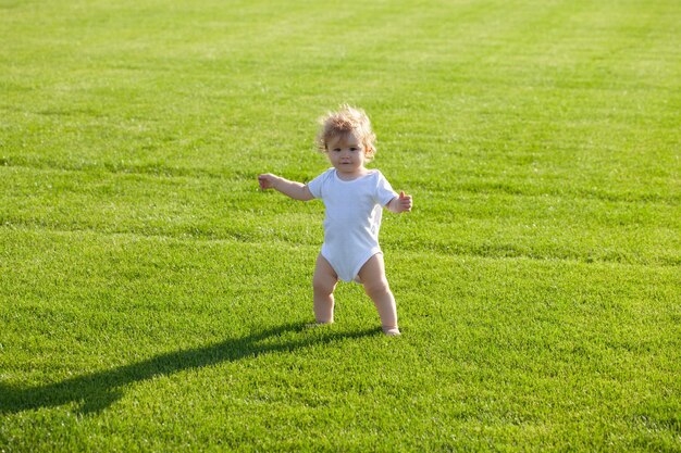 bebé, posición, descalzo, en, el, césped verde, niño sano