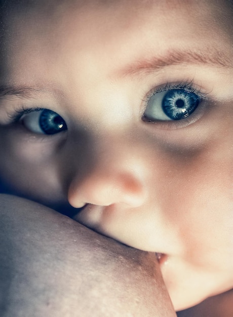 Bebé que amamanta con ojos azules limpios closeup