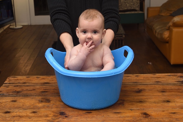 Bebé que se baña en un balde en casa