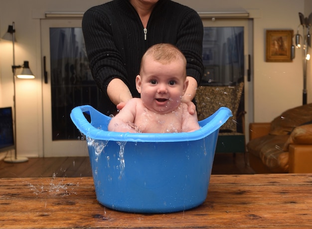 Foto bebé que se baña en un balde en casa