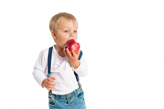 Bebé que come la manzana y que sonríe en el estudio aislado