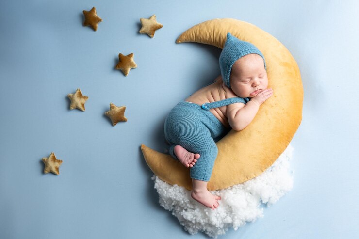 Foto bebê recém-nascido deitado na lua em um fundo azul menino em um terno azul
