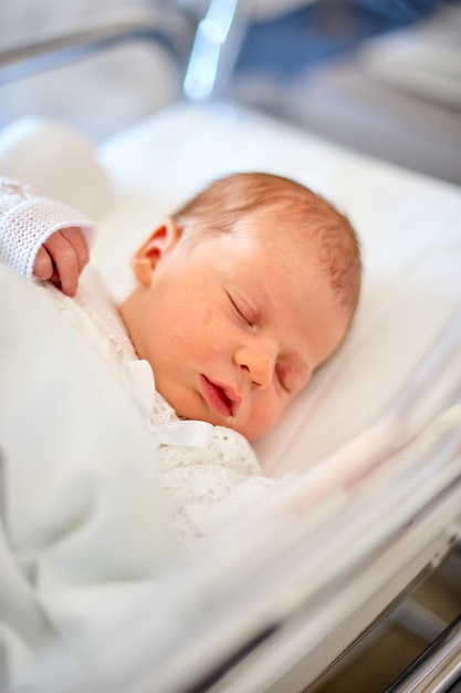 Bebê recém-nascido dormindo em seu berço de hospital