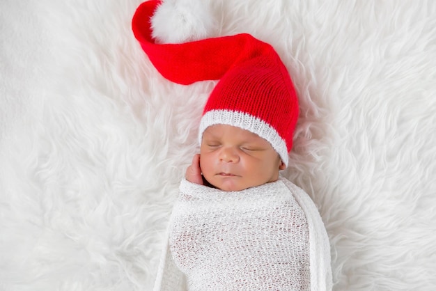 Bebê recém-nascido dorminhoco em um boné de Papai Noel de Natal