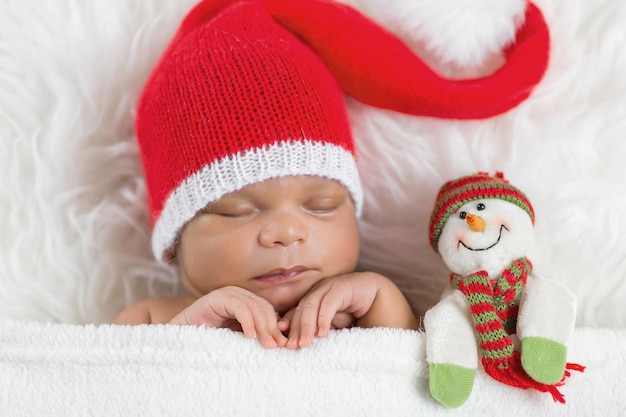 Bebê recém-nascido dorminhoco em um boné de Papai Noel de Natal