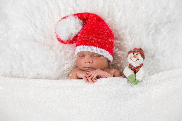 Bebê recém-nascido dorminhoco em um boné de Papai Noel de Natal