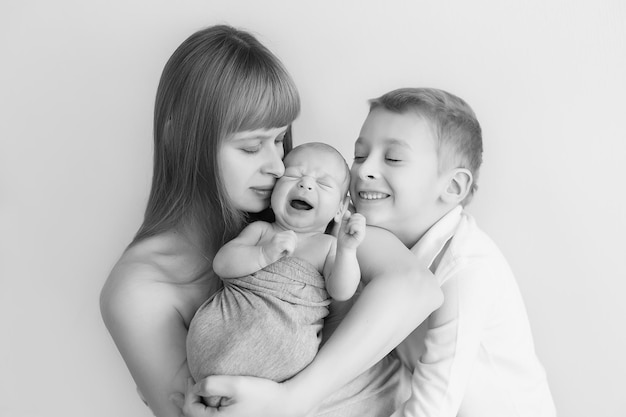 bebê recém-nascido nos braços da mãe e do filho mais velho, foto em preto e branco, monocromática. cuidado paterno