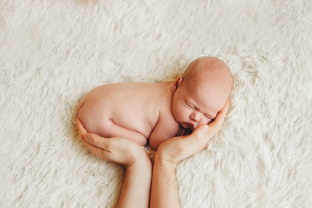 Bebê recém-nascido nu, deitado nas mãos dos pais