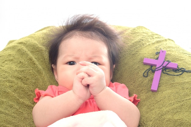 Foto bebê recém-nascido orando com uma cruz