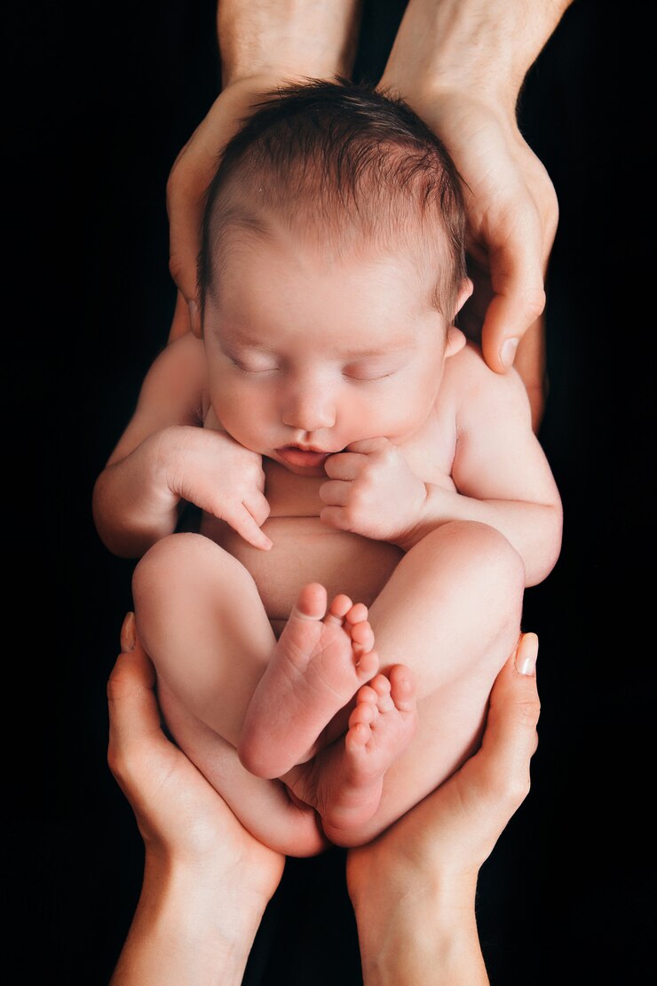 Foto bebê recém-nascido que encontra-se nas mãos dos pais em um fundo preto. imitação de um bebê no útero.