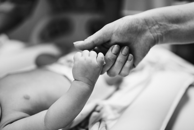 Bebê recém-nascido segurando a mão da mãe com amor