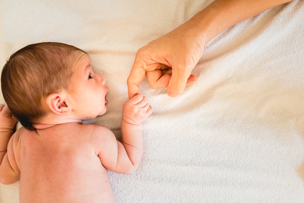 Foto bebê recém-nascido segurando com segurança as mãos de sua mãe, dedos close-up.