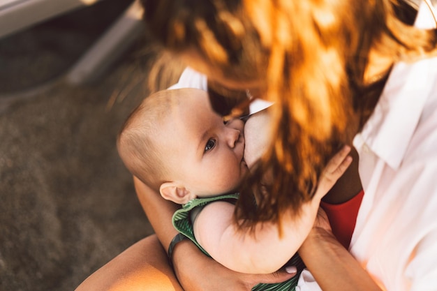 Bebê recém-nascido sugando leite do seio da mãe na praia