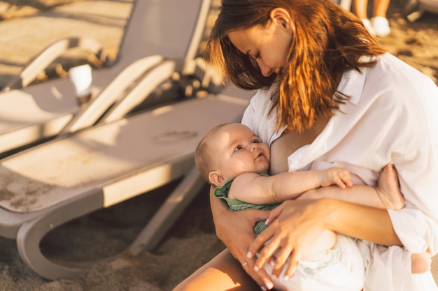 Bebê recém-nascido sugando leite do seio da mãe na praia