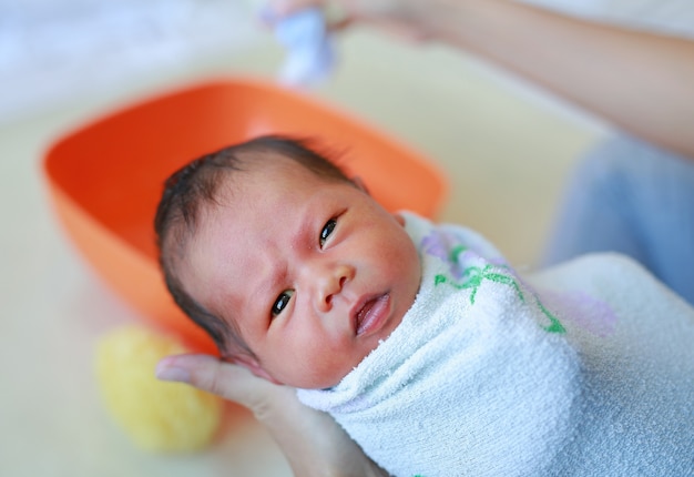 Bebê recém-nascido tomando banho pela mãe.