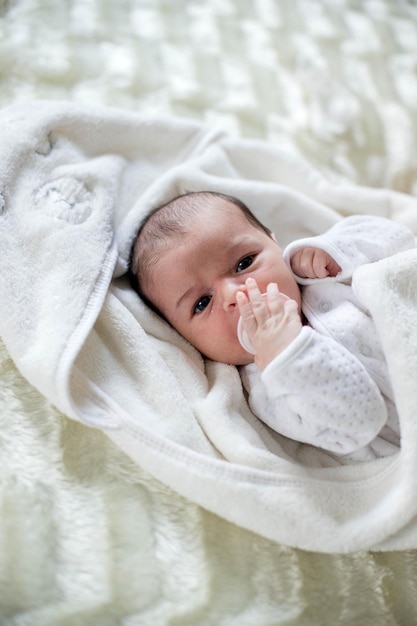 Foto bebé recién nacido acostado cubierto con una manta blanca