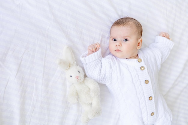 Foto el bebé recién nacido está acostado en una cuna en un mono blanco cálido en una cama de algodón aislada blanca bebé saludable dormir de cerca