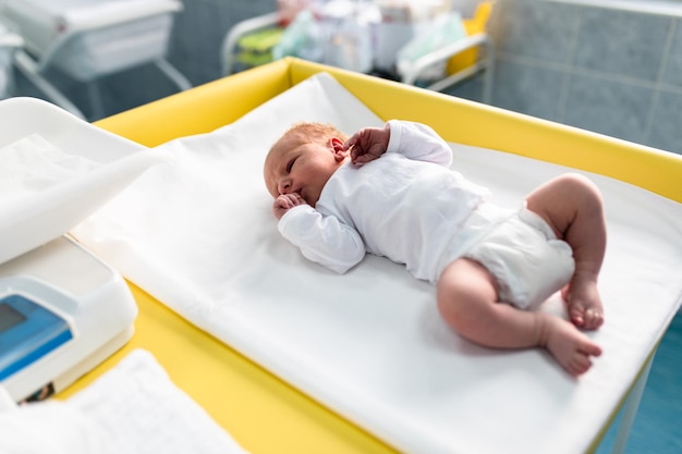 Bebé recién nacido acostado y deslizándose en la cama de la sala de maternidad. Después del concepto de nacimiento.