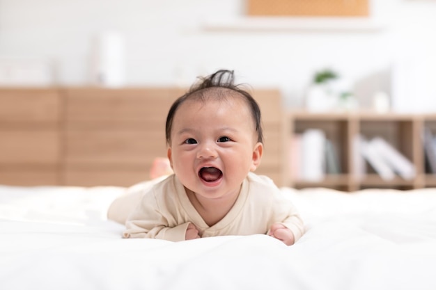 Foto el bebé recién nacido acostado en el estómago desarrollando el control del cuello el tiempo de la barriga para fortalecer los músculos del cuello y los hombros del bebé el bebé lindo acostado arrastrándose en la cama blanca la felicidad y la diversión el concepto de tiempo de barriga